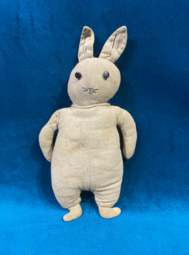 Vintage stuffed rabbit toy with worn fabric and stitched features displayed against a blue background.
