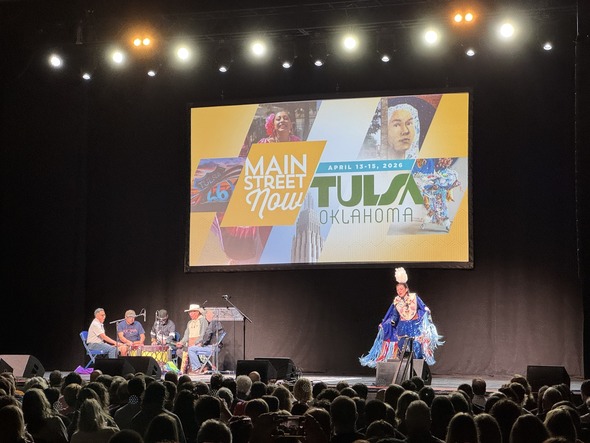 Main Street Now conference stage in Tulsa with performers and large screen above audience.