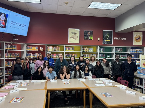 Group of middle school students and staff posing in a library during AVID program visit.