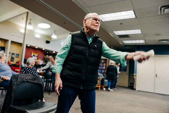 A man playing Wii bowling standing in a well-lit room