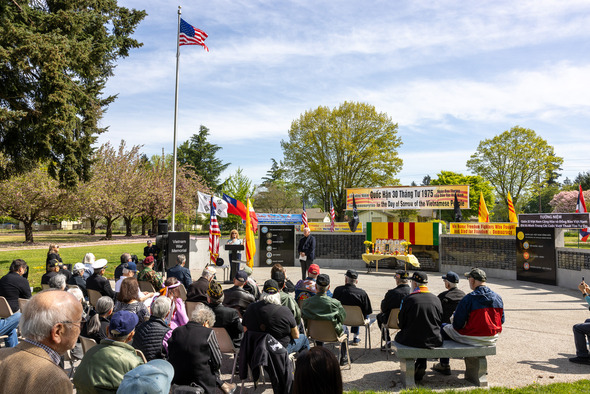 Crowd gathers at Auburn Vietnam War Memorial for ceremony with flags, speakers, and tributes honoring the fall of Saigon.