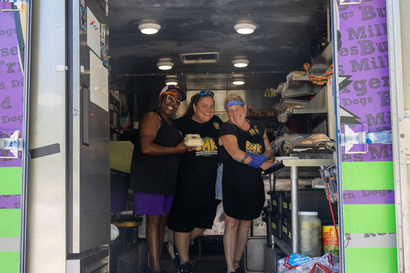Three women standing in a food truck smiling at the camera