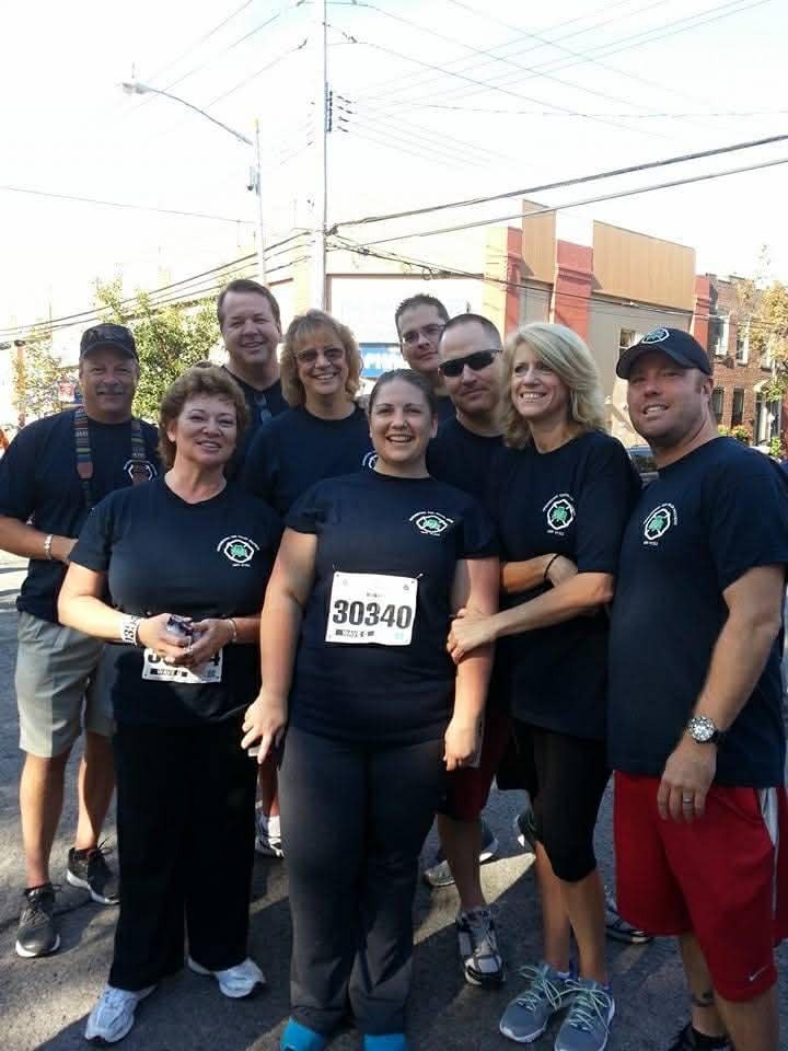 Group of runners in matching shirts pose together outdoors before a race.
