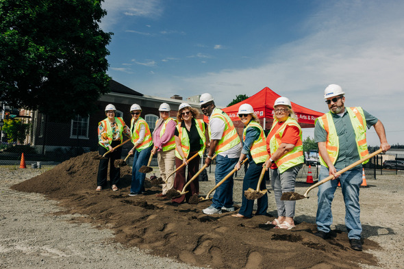 City officials in hard hats and safety vests pose with shovels at a groundbreaking ceremony.