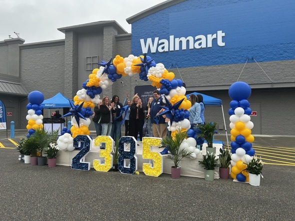 A group of people cutting a ribbon up on a Walmart stage