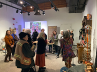 Visitors gather inside a gallery to view a mixed-media art exhibit.