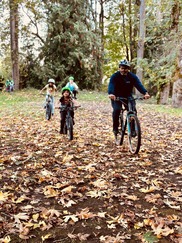 group riding bikes in a line during the fall, with leaves on the ground