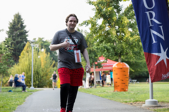 An Almost 5K participant gives a thumbs-up while walking through an Auburn park.