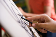 Close-up of a hand using scissors to cut white fabric.
