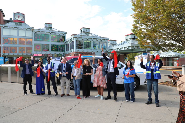 Group celebrates Metro Flex service with red ribbons outside Auburn Station.