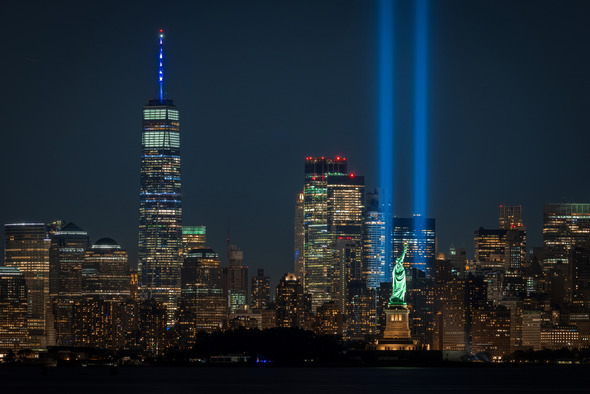 New York City skyline at night with bright blue lights shining high 