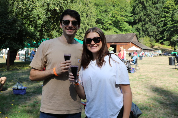 Smiling couple holds tasting glasses at Hops & Crops at Mary Olson Farm.