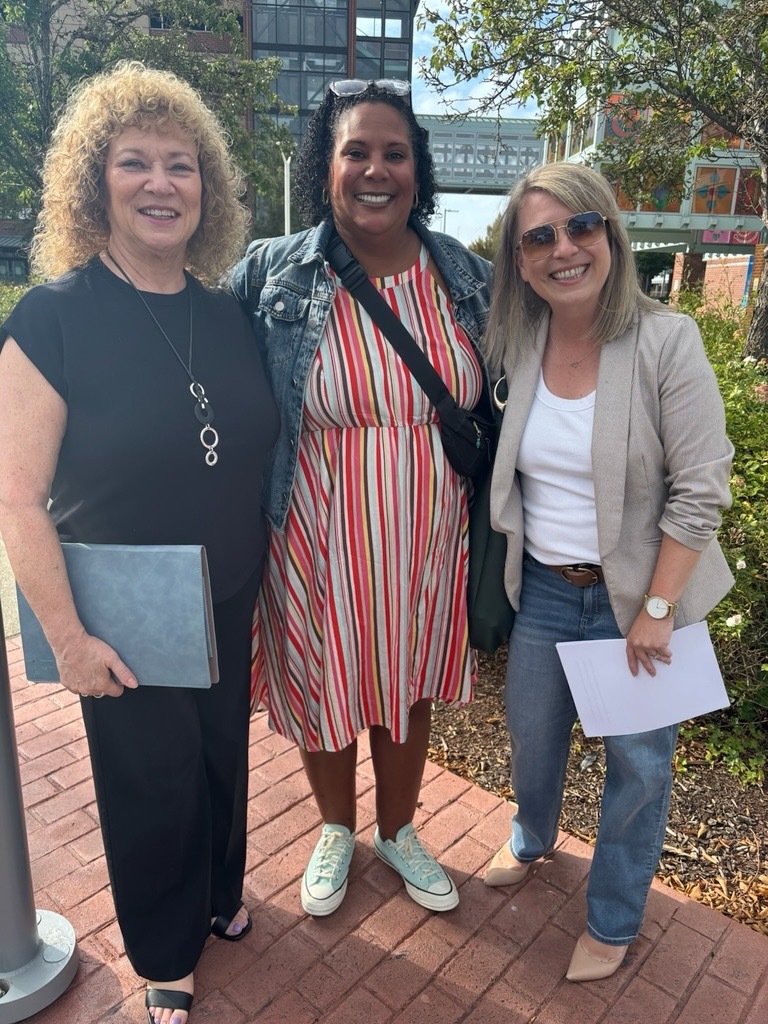 Three women smile together outside Auburn Station following a Metro Flex celebration.