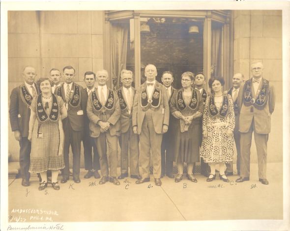 Sepia-toned 1927 photo of men and women wearing ceremonial sashes outside a building in Auburn