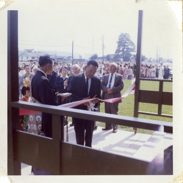 Historic photo of a ribbon-cutting ceremony attended by a large crowd gathered outside a building.