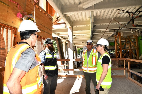 Building safety professionals gather in front of elevator in building under construction wearing safety gear