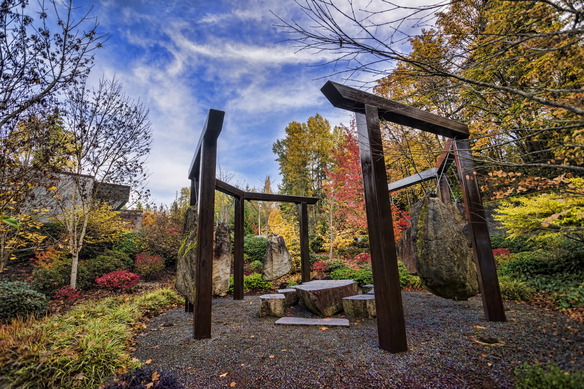 Image shows exterior art and a seating area in the middle of greenery and trees 