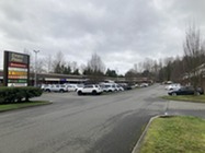 Image shows the parking lot of Evans Plaza with cars parked; the sign for the plaza and business located in it is also visible.