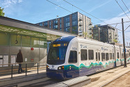 Photo shows BelRed light rail station with housing behind.