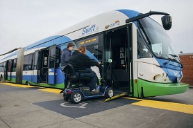 A person using a wheelchair  boards a Swift Blue Line bus