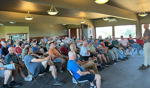 A large group of people sits while listening to Parks and Recreation Director Andy Coleman
