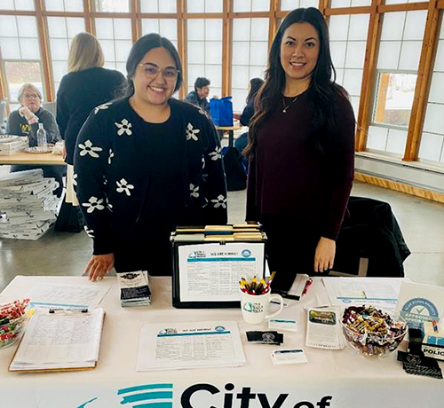 Two City of Walla Walla Human Resources staff members stand with a table of employment materials