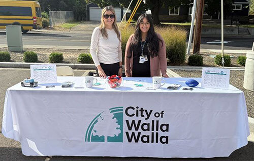 Two City employees stand with a table of employment materials