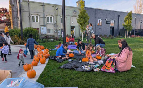 Families carve pumpkins on the grass at Heritage Square in Walla Walla