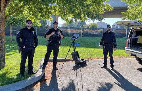 Three police officers prepare to launch a drone during a police operation