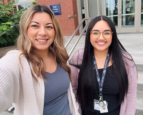 Two City of Walla Walla HR employees take a selfie in front of Reid Campus Center at Whitman College