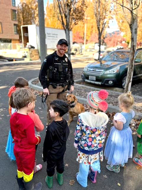Police officer holds the leash of a K9 officer while eight preschool-age children look on