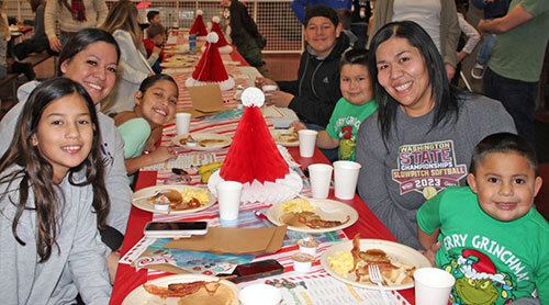 Parents and children sit at tables covered with holiday decoration and plateware in Walla Walla's Fire Station 1