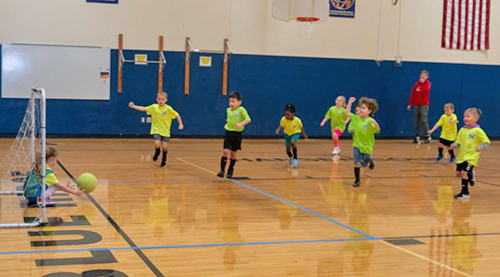 Children play soccer in a gymnasium