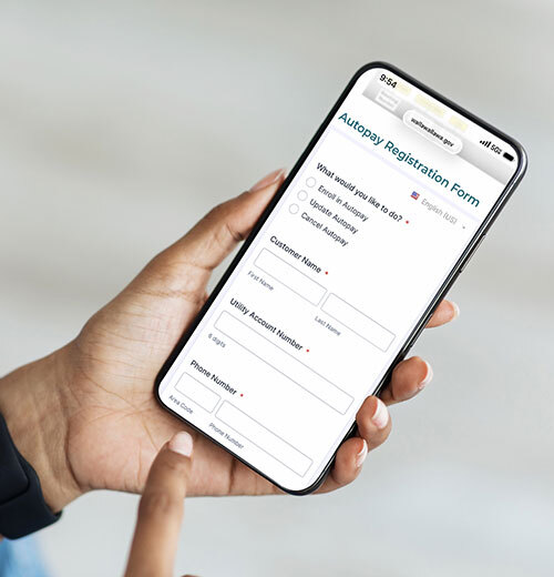Hand holding a cellphone showing the Autopay Registration Form on a browser