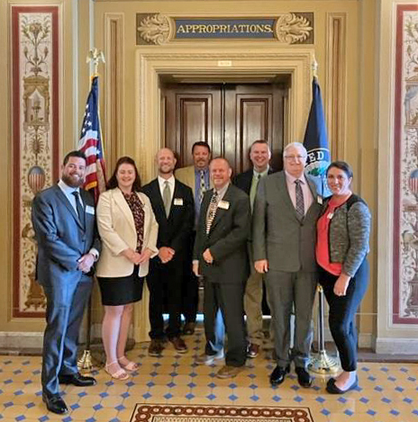 Eight people stand in the U.S. Capitol in front of a door labeled Appropriations