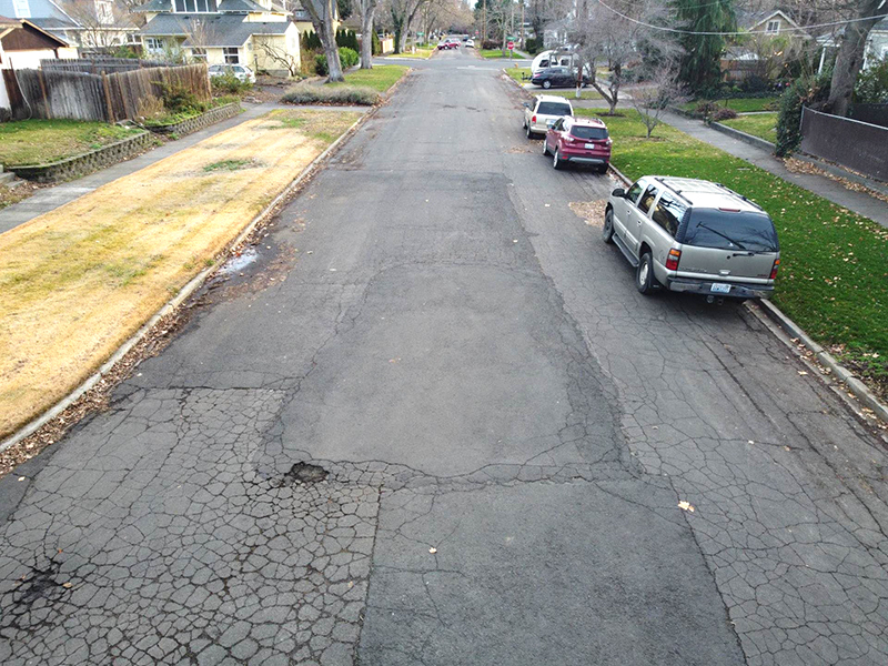 Residential street in Walla Walla with various types of damage to its asphalt