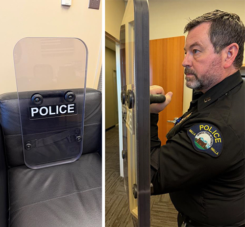 Police officer in uniform holds a transparent, 2-inch-thick, rectangular shield