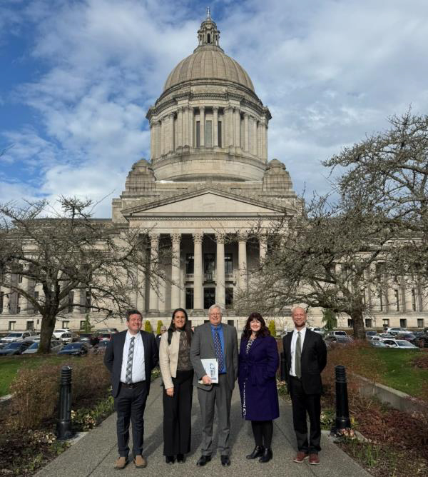 Five people stand in front of the Washington State Capitol Building in Olympia