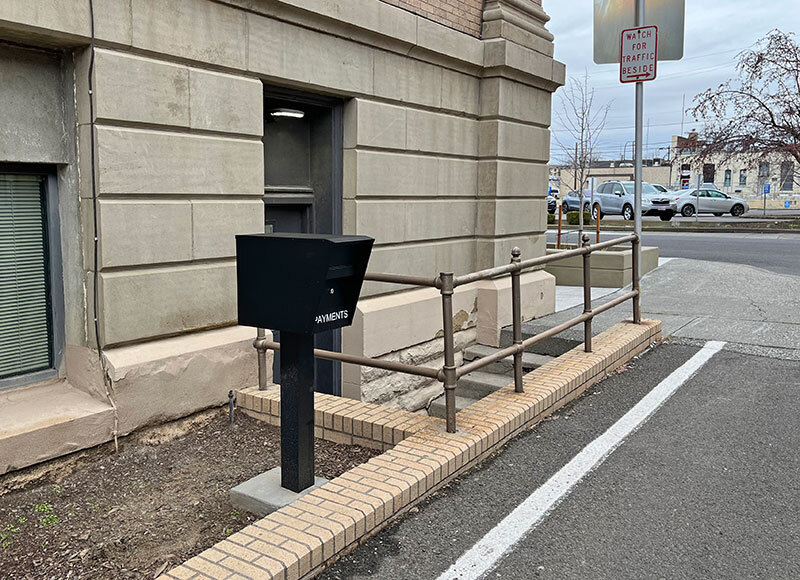 A black drop box on a post in the alley next to Walla Walla City Hall