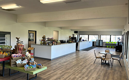 Long room with windows along the walls with snacks, counters, desk area, and golf pro shop