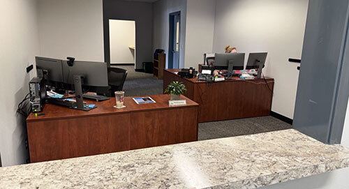 Two desks in an office area with a window and counter