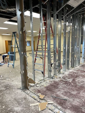 Metal studs with drywall removed in a former wall between rooms