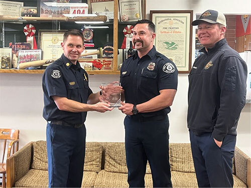 Fire chief hands a glass award to a firefighter