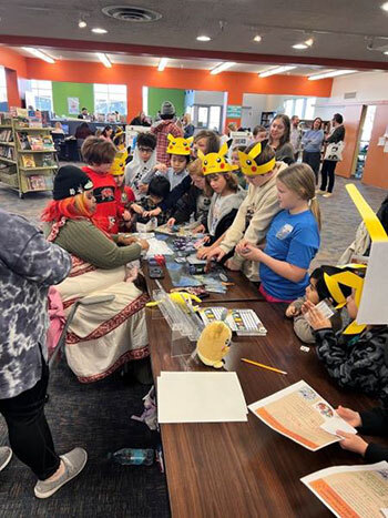 Children — many wearing Pikachu headbands — do Pokémon-related crafts in the library