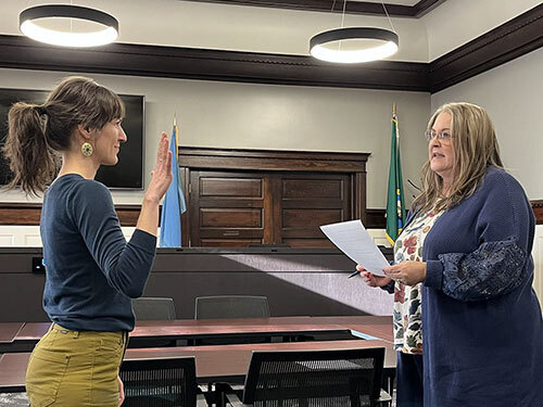 Emily Brown holds her hand up while taking the oath of office while City Clerk Lisa Neissl reads the oath