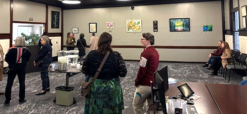 People converse and view art hanging on the walls in the City Council Chambers in City Hall