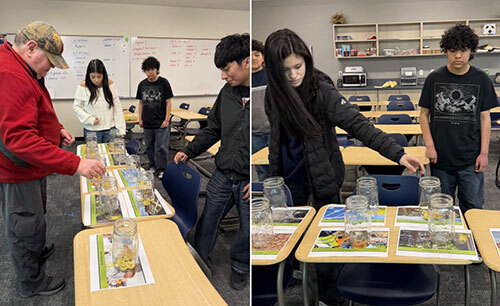 High-school students place coins in jars in a classroom