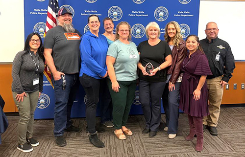 Nine dispatch personnel pose for a photo, one of whom is holding an award