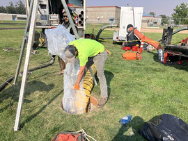 Worker guides what looks like a long plastic bag into a sewer access hatch