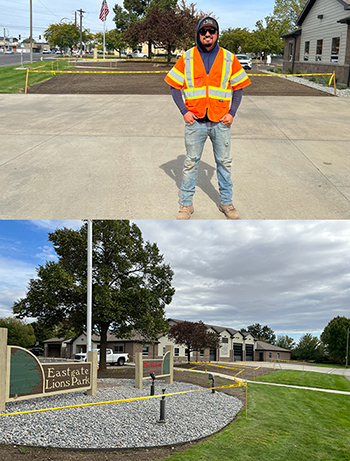 A worker wearing safety vest stands next to a taped-off area planted with grass seed in front of a fire station